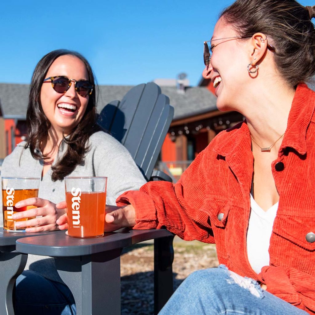 Two Girls Enjoying Stem Ciders Outdoors